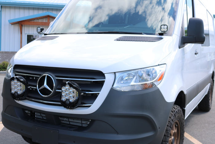 HOODLINE LIGHT POD MOUNT - SPRINTER (2019+) by VAN COMPASS: Close-up of a white van's hood, showcasing easily installed LED pod mounts attached to the factory hood hinge studs.