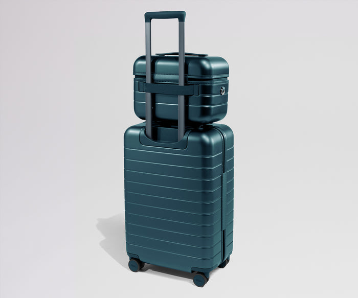 Teal suitcase with a smaller teal suitcase on top against a light gray background