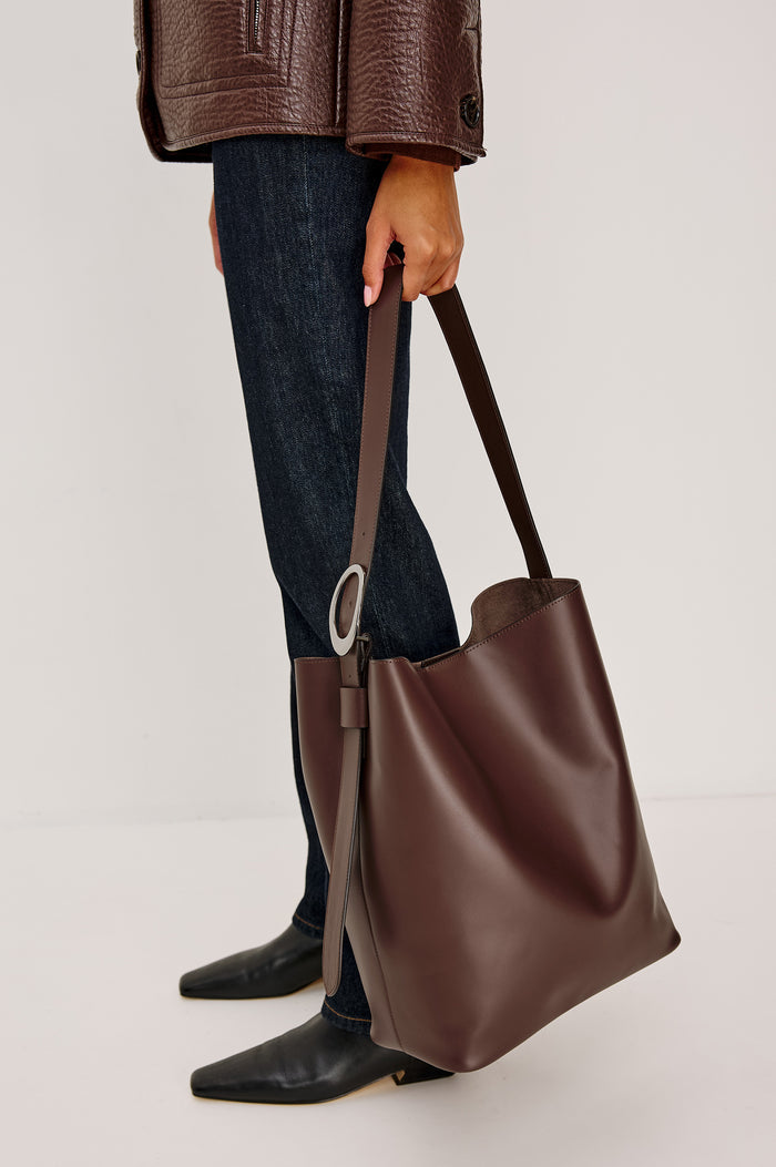 Torino Bucket Bag in Italian Leather With Adjustable Strap and Polished Silver Oval Buckle, Microsuede Lining, Interior Magnetic Closure, Snap Button-Slip Pocket, and Subtle Branded Detailing in Cowgirl Haircalf Colorway Colorway - Stylized on Model View Featured