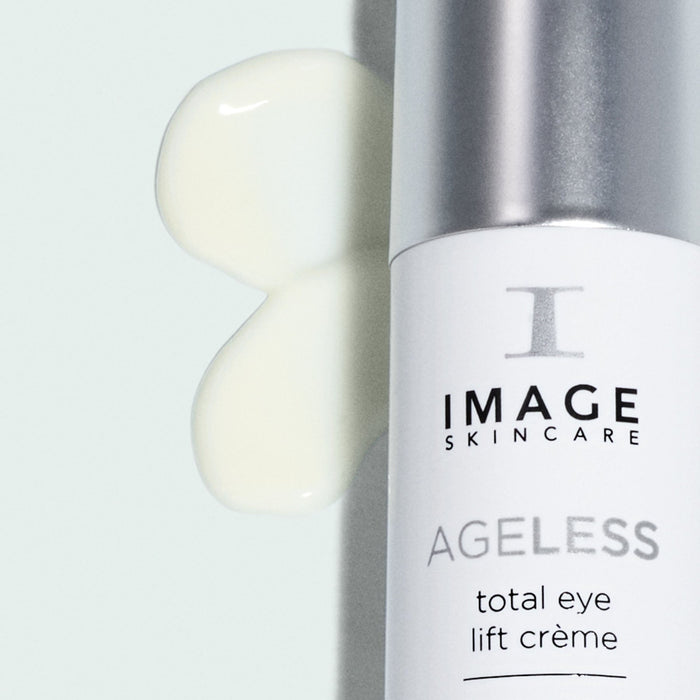 Close-up of a bottle of AGELESS total eye lift crème | IMAGE Skincare with a smooth cream texture swatched beside it, highlighting skincare and body care product quality.