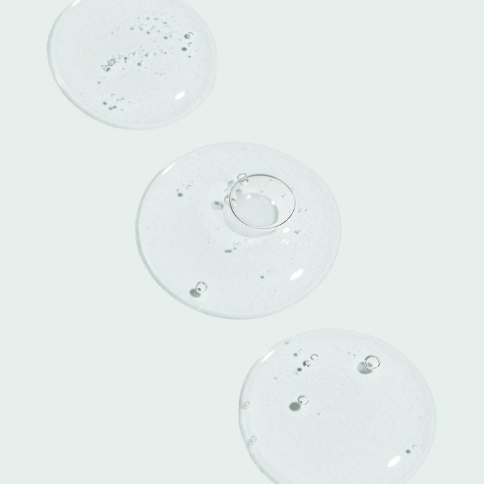Clear gel droplets with small air bubbles on a light background representing the texture of AGLESS total pure hyaluronic 6 filler | IMAGE Skincare for skincare and wellness supplements.