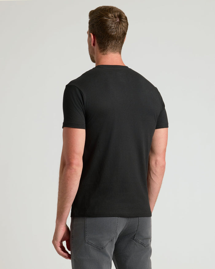 Back view of person in All Black Crews T-shirt and gray jeans.