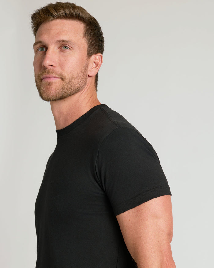 Man wearing a fitted black t-shirt looking off to the side, showcasing the style of the All Black Classic Crews 10-Pack men's basics.
