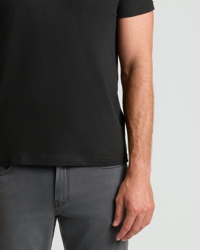 Person wearing a black t-shirt and gray pants on a light gray background