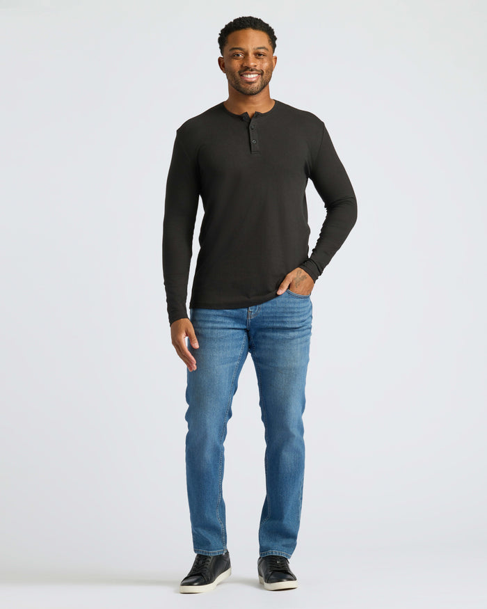 Man in Black Long Sleeve Henley, jeans, sneakers, smiling.