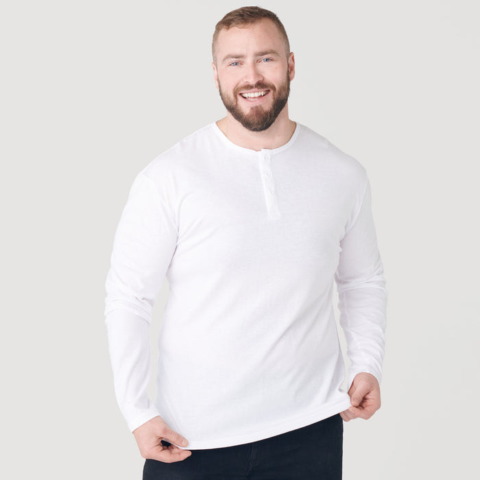Man wearing White Classic Long Sleeve Henley, smiling, and adjusting hem.