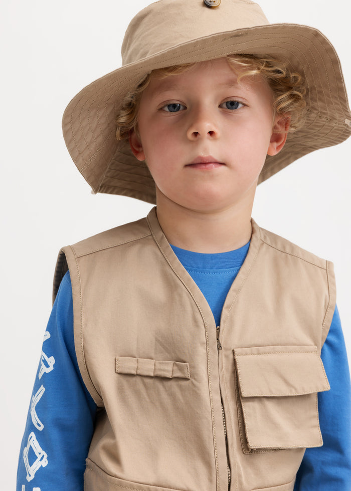 A yellow beanie in beige for children with a wide brim and a button in front.