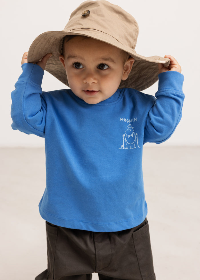 A small child's beanie hat in beige with a wide brim and adjustable edge.