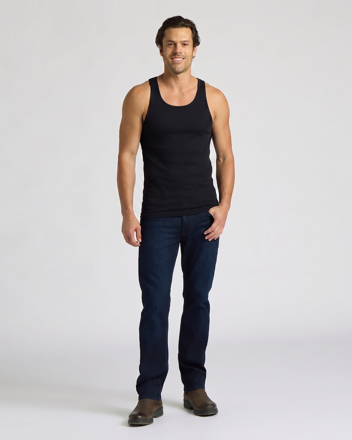 Man wearing a black tank top and dark blue jeans on a white background