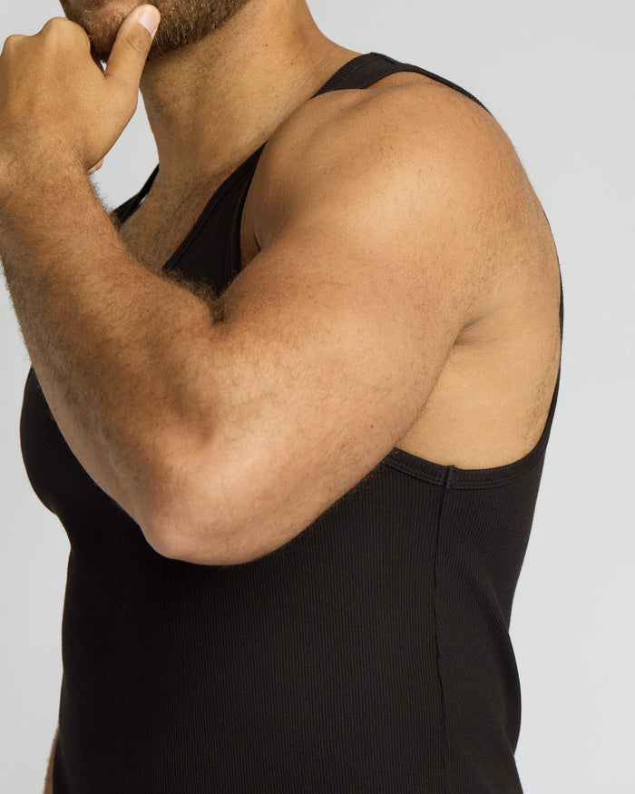 Person wearing a black tank top against a plain background