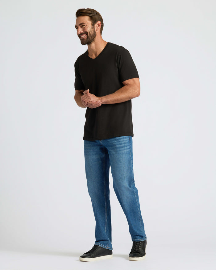 Man wearing Classic V-Neck with jeans and sneakers, smiling.
