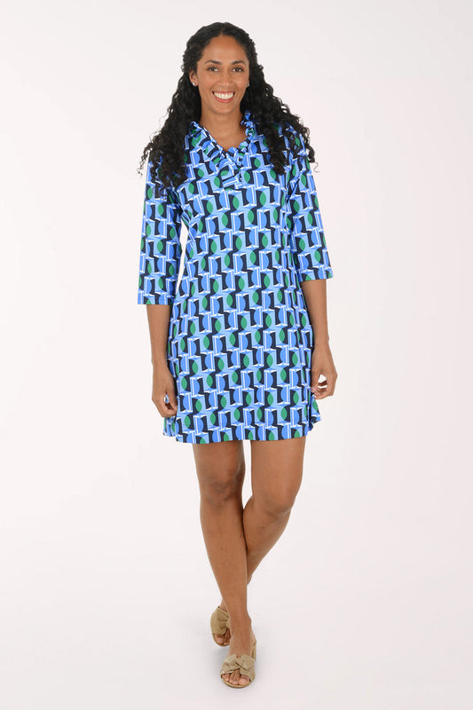 A woman modeling a short-sleeve button-up shirt dress with a blue, green, and white geometric pattern, standing against a plain white studio background.