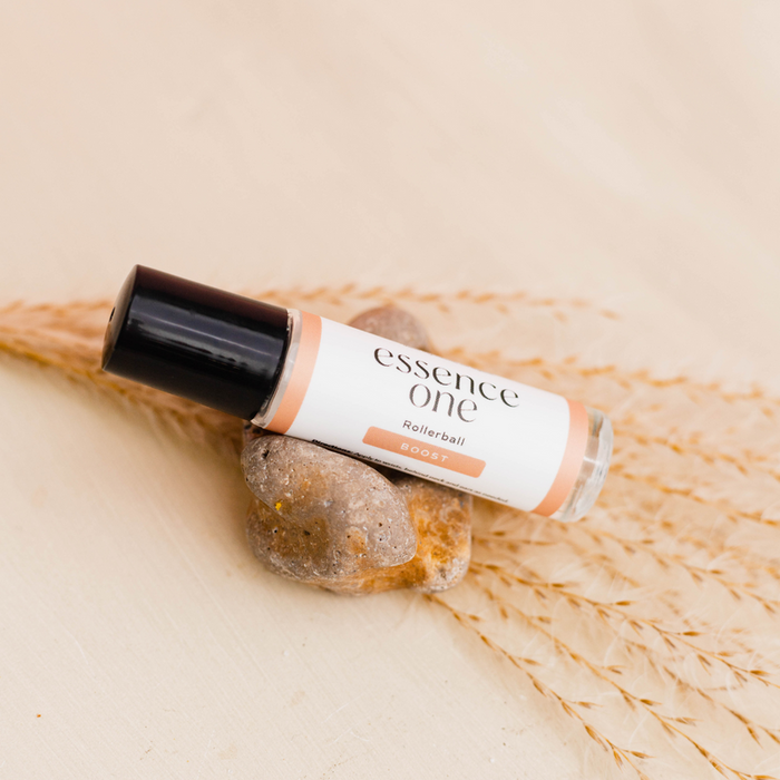 Boost Rollerball - Immune Support | Essence One, a wellness supplement in a sleek rollerball bottle, resting on natural stones and dried wheat for a calming presentation.