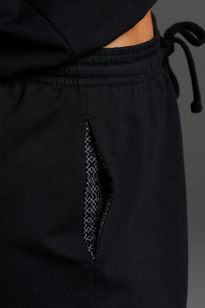 Black pants with a textured pocket detail on a gray background || Black