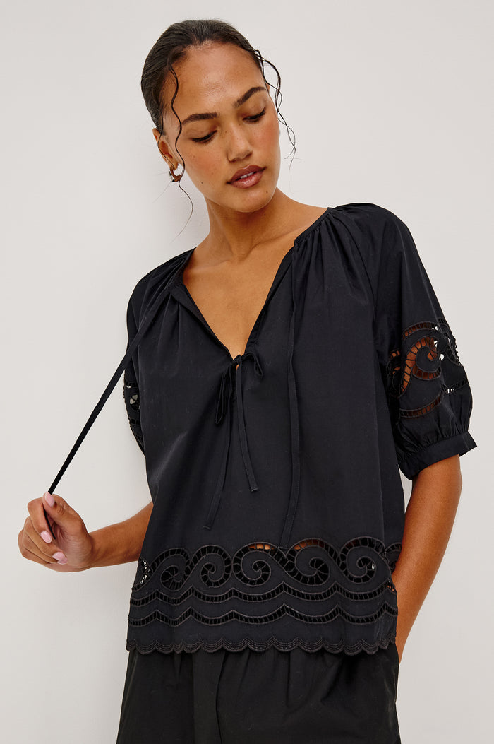 Catalene Peasant Blouse in Poplin With Self-Tie V-Neckline, Sheer Embroidered Detailing, Loose Fit, and Short Puff Sleeves in Black Colorway - Upper Body Front View Featured on Model