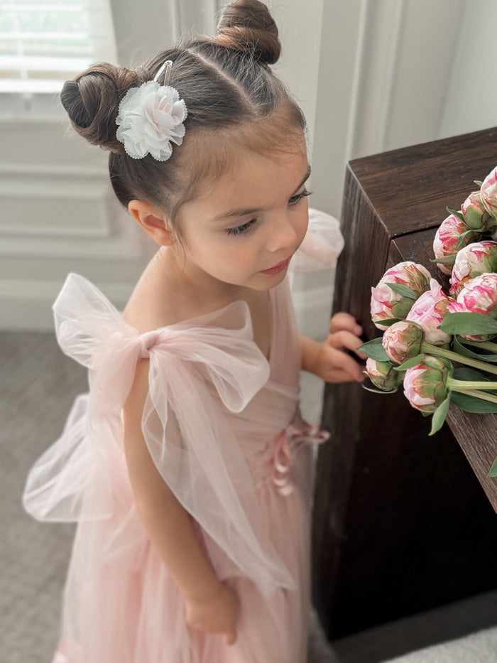 Cherry Blossom white and pink hair clip worn in a double bun hairstyle, adding a soft floral touch to a formal girls look