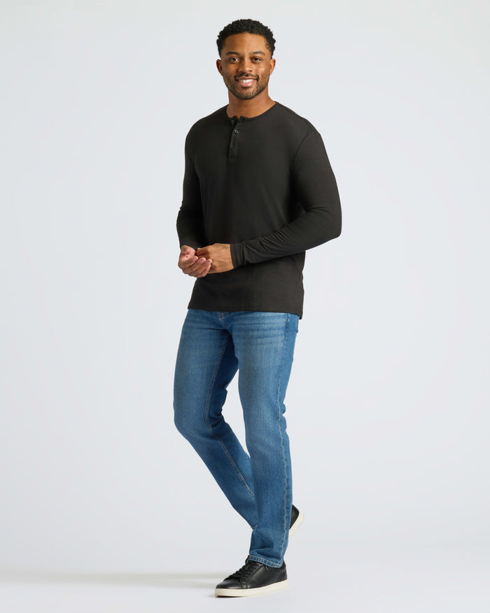 Man wearing Black Long Sleeve Henley with jeans and sneakers.