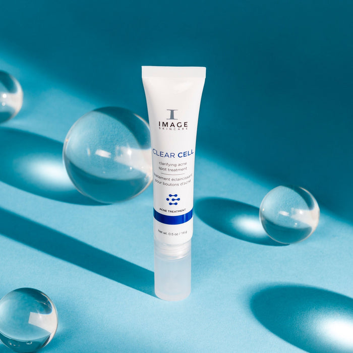 CLEAR CELL clarifying acne spot treatment | IMAGE Skincare tube standing on a blue surface with glass spheres and soft shadows, representing skincare and wellness supplements.