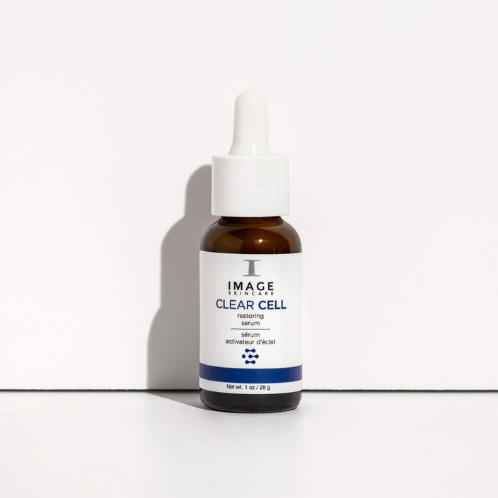 Brown glass dropper bottle of CLEAR CELL Restoring Serum | IMAGE Skincare on a white surface, showcasing a skincare product for skin restoration and wellness.
