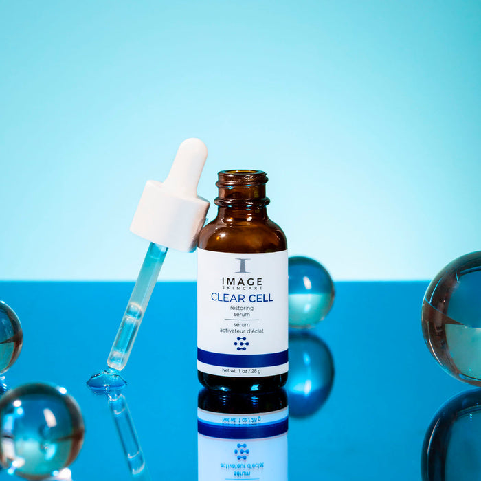 CLEAR CELL Restoring Serum | IMAGE Skincare bottle with dropper, surrounded by glass spheres, highlighting skincare and wellness supplements on a blue background.