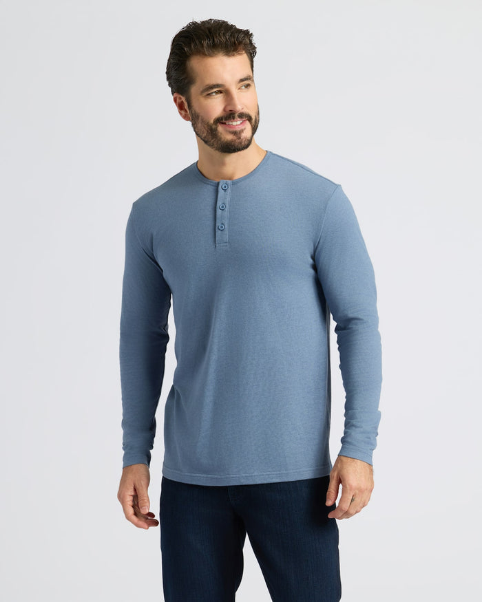 Man wearing Dark Heather Vintage Navy Classic Long Sleeve Henley, smiling slightly.