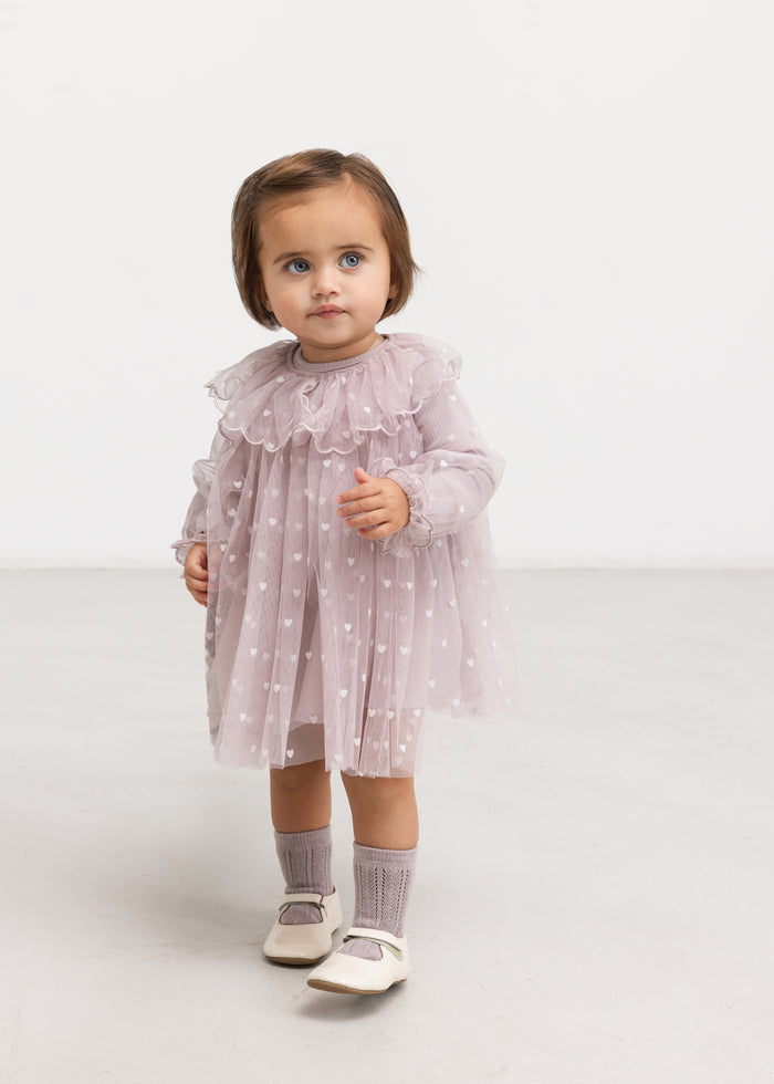 Elegant pink dress with heart print and ruffled collar, paired with stockings.