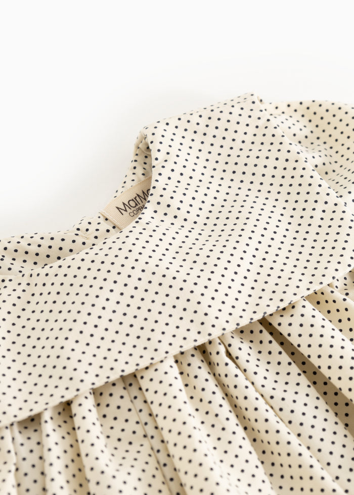 Crave and button closure on a polka-dot baby dress with small dark dots.