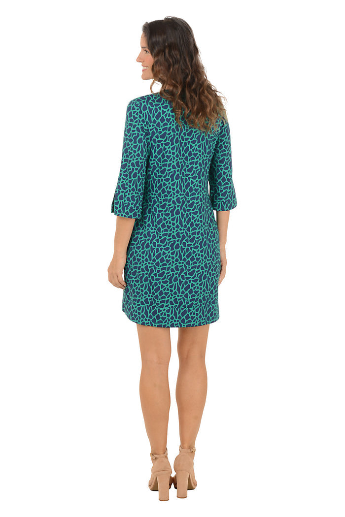 A woman modeling a short teal and black leopard-print dress with three-quarter bell sleeves and a split neckline, paired with beige high-heeled sandals against a plain white background.