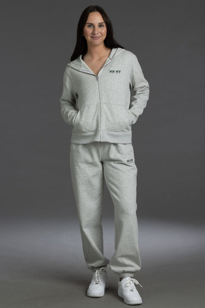 Woman wearing a gray tracksuit with a brand logo on a gray background || Light Heather Gray