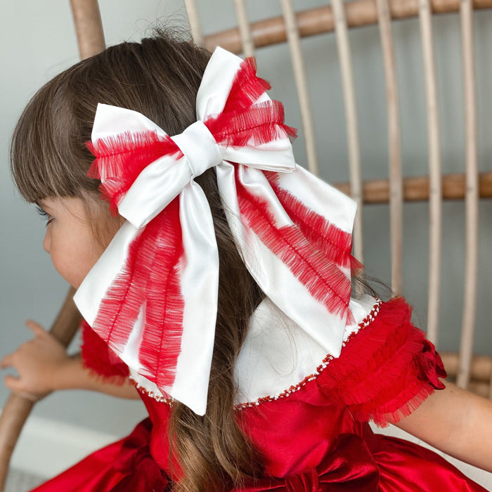 Holly Ruffle Hair Bow styled in girl's hair, red and white layered satin bow perfect for Christmas outfits.