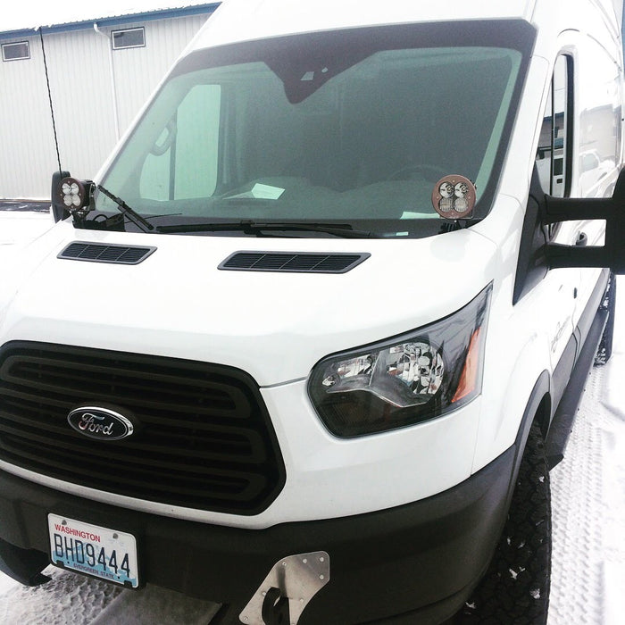 HOODLINE LIGHT POD MOUNT - TRANSIT (2013+) by VAN COMPASS. Close-up of a white van's front, highlighting the headlight area where the mounts install.