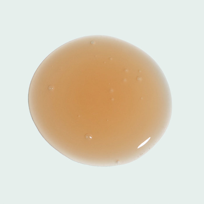 A single drop of light amber serum showcasing its smooth, translucent texture for ILUMA® intense brightening serum | IMAGE Skincare, highlighting skincare and wellness.
