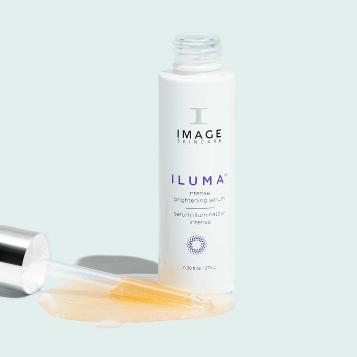 Bottle of ILUMA® intense brightening serum | IMAGE Skincare with dropper and serum spilled on a light background, showcasing skincare product for brightening and wellness.