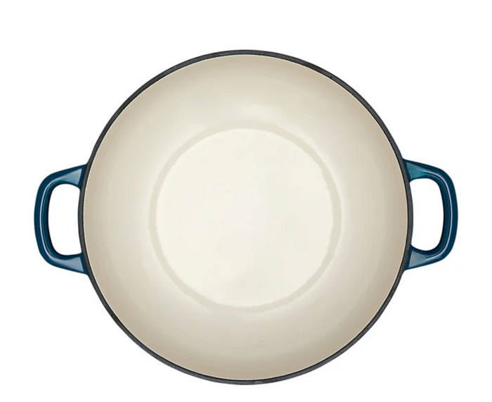 White interior of a blue enameled cast iron Dutch oven on a white background.