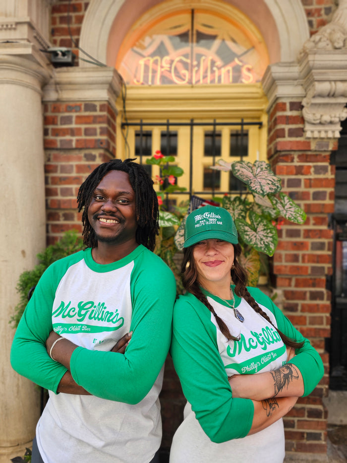 green and white baseball t-shirts with 'McGillin's' text on them, in front of pub entrance.