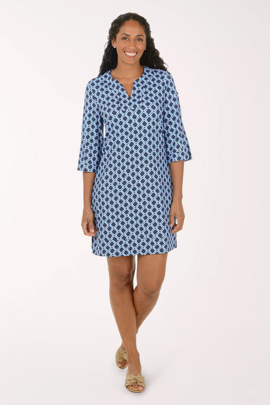 A woman modeling a short blue and white patterned tunic dress with three-quarter sleeves and a split neckline, standing against a plain light background.