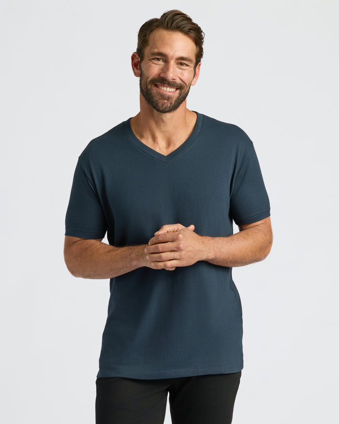 Man wearing Classic V-Neck T-shirt, smiling with hands clasped.