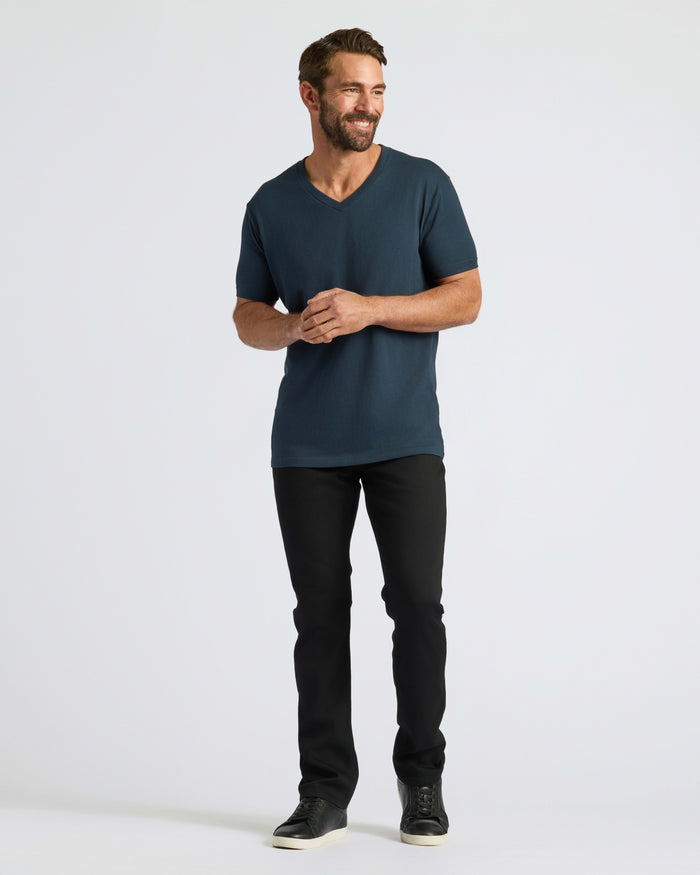 Man wearing Classic V-Neck with slim-fit pants, sneakers. Smiling.