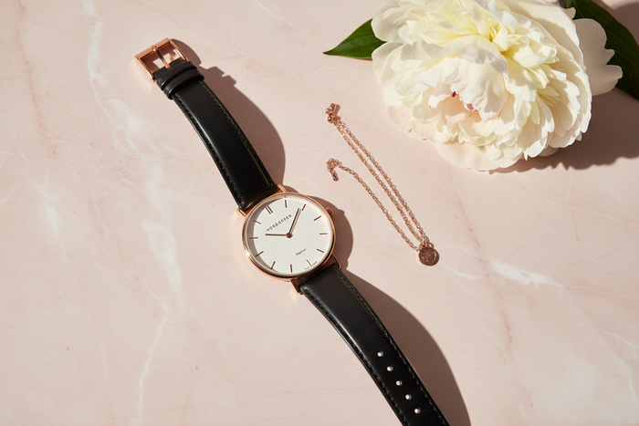 Nordgreen Native 32mm Rose Gold Case Black Leather watch flat lay on blush marble with white peony