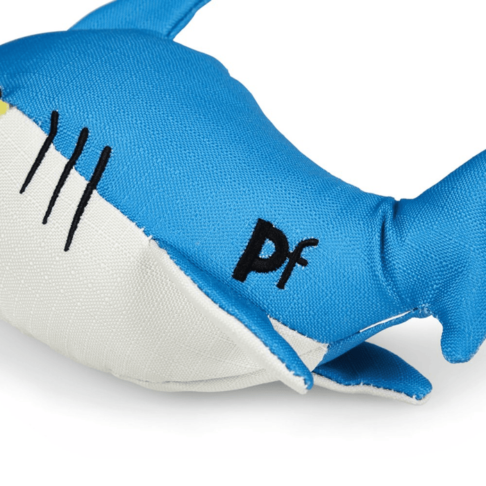 Close up of blue plush shark dog toy with a white belly, stitch text 'PF' detailed on tail on a white background.