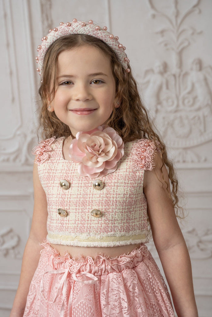 Pink flower neck tie worn at neckline by child, showcasing soft layered rose detail with a vintage inspired blush outfit