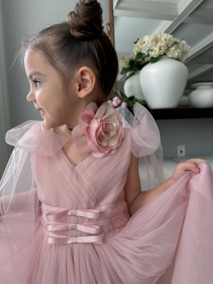 Child wearing pink flower neck tie highlighting the details and textures of the item