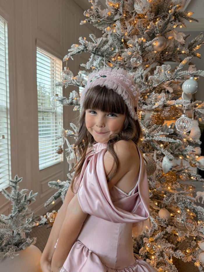 Pink ballerina hair sash featuring pleated fabric and ribbon ties, worn by a young girl during a festive holiday photoshoot