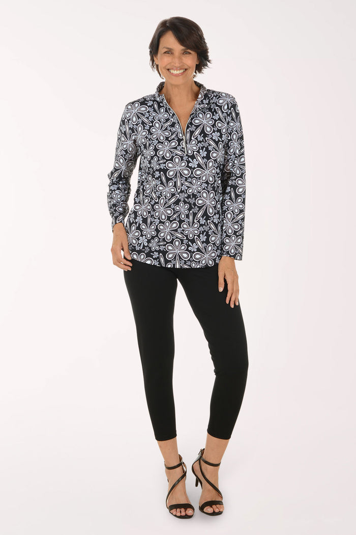 A woman modeling a long-sleeve button-up blouse with a black, white, and gray paisley pattern, paired with black cropped pants and black strappy high-heeled sandals, against a plain white studio background.