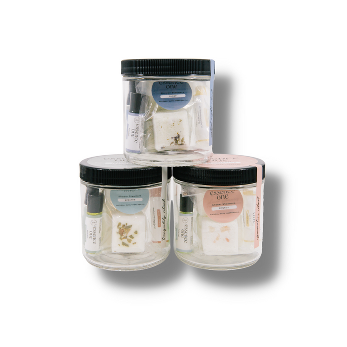 Three clear jars containing natural skincare products with herbs and oil bottles, labeled as Ritual Kit | Essence One, promoting wellness and body care.