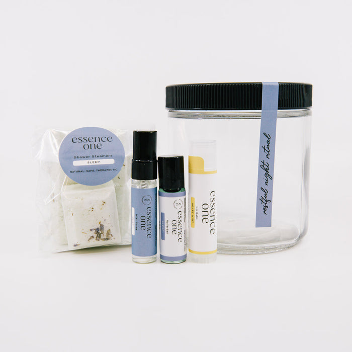 Ritual Kit | Essence One featuring a clear jar with black lid and pastel-labeled wellness supplements including sleep soak, roller, and balm for skincare and relaxation.