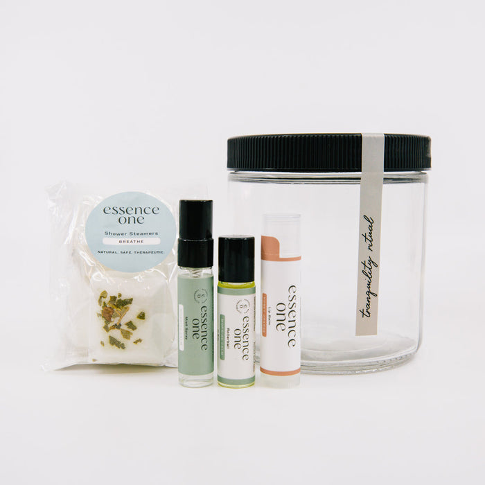 Ritual Kit | Essence One featuring a clear storage jar and a set of wellness items including shower steamers, aromatherapy sprays, and a lip balm.