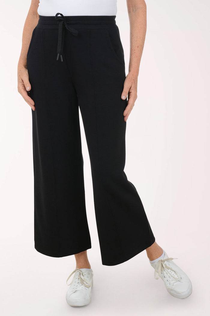 Person wearing black wide-leg pants on a white background