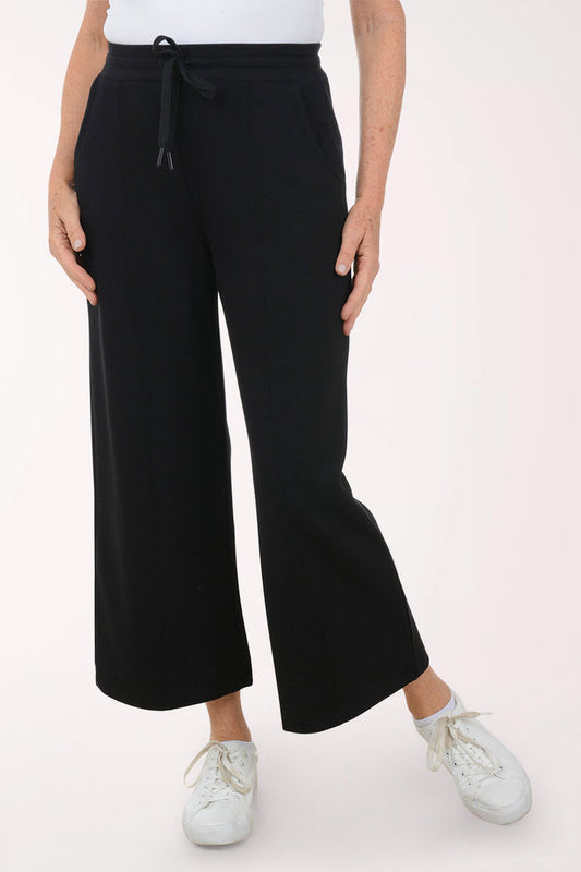 Person wearing black wide-leg pants on a white background