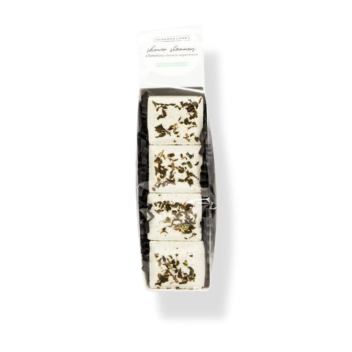 Stacked white Shower Steamer | Essence One with dried herbs on top, packaged in a clear wrapper for an aromatic wellness spa experience.
